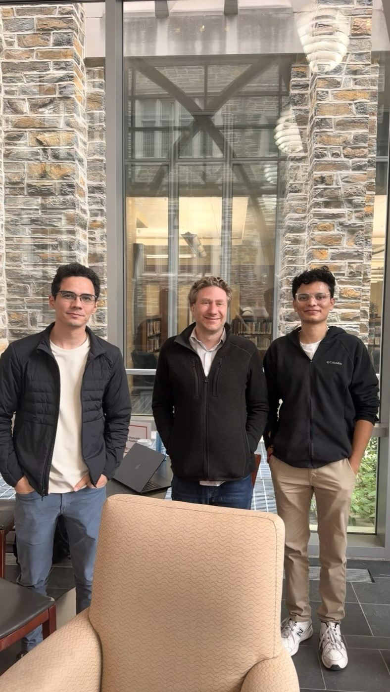 Three people standing in front of a glass and stone wall at Duke after YC office hours
